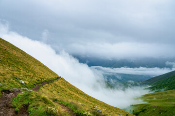 Fototapeta na wymiar Kazbegi, Georgia - Mountain landscape of Mount Kazbegi landscape with dramatic clouds up in the trekking and hiking route.