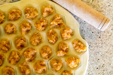 Raw homemade dumplings. Chicken meat with spices on the dough. The process of making dumplings