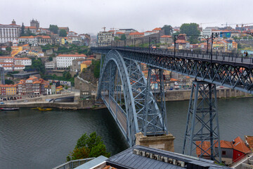 Fototapeta na wymiar The Dom Luis I Bridge over the Douro River and the colorful houses of Porto Ribeira, traditional facades, old multi-colored houses with red roof tiles on the embankment in the city of Porto, Portugal.
