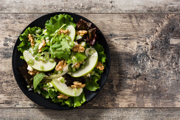 Fresh Waldorf salad with lettuce, green apples, walnuts and celery on wooden table. Top view. Copy space
