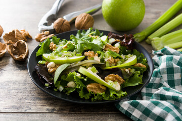 Fresh Waldorf salad with lettuce, green apples, walnuts and celery on wooden table.