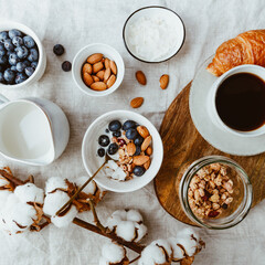 Obraz na płótnie Canvas .Breakfast table with muesli, almond, blueberry, coconut flakes, milk, coffee and croissant.