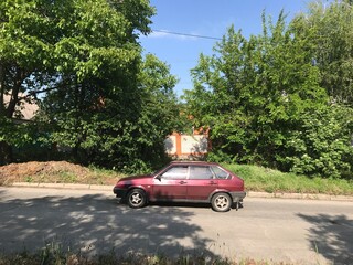 Old car burgundy color rides on the asphalt road in the afternoon