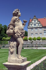 Close-up view from the side of the sandstone statue of Bacchus, the god of wine, in the garden of Weikersheim Castle (in the background), Hohenlohe Region, Tauber Valley, Germany, Europe