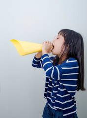 Lettle girl shouting into megaphone with white background.