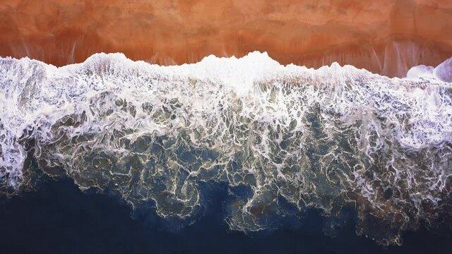 Flying over a sandy beach. Waves break on a sandy beach on the Atlantic coast, aerial View. Nazare, Portugal.