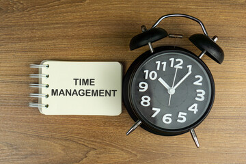 alarm clock on wooden table with TIME MANAGEMENT word