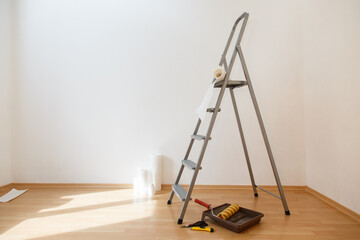 stepladder ready to work in the room. Wallpaper gluing in a room. Tools for gluing white wallpapers. White room after renovation. Fresh repair in a room