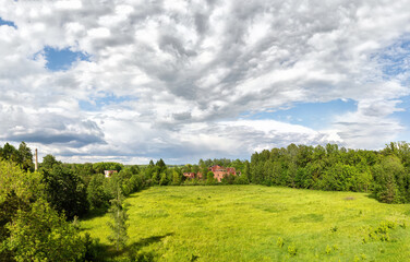 Panoramic landscape with red brick house ruins in the park on cloudy summer afternoon