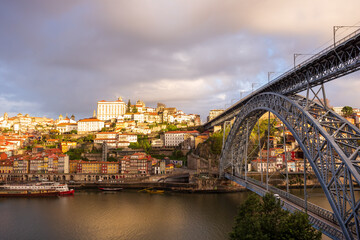 Naklejka premium Morning in Porto Portugal: Douro river and Ribeira district featuring Ponte Luis I bridge and sunlit Episcopal palace on the top of the hill.