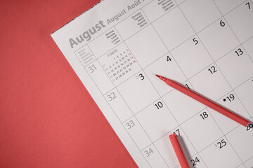 Red pencil or pen on open calendar and the red background. Business planning concept.