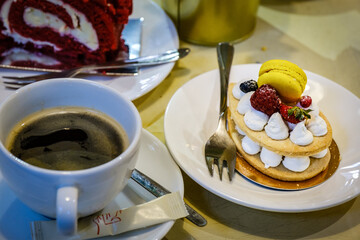 cup of coffee and a cake of cookies and meringues on a table in a cafe.