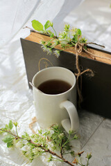 Tea mug, brown book and green plant branches