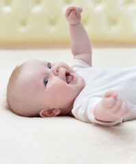 Cute little baby girl lying on her back and smiling