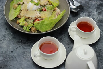 Food photography. Fresh vegetable salad, chicken, eggs with a sprinkling of delicious seasonings and two cups of warm tea