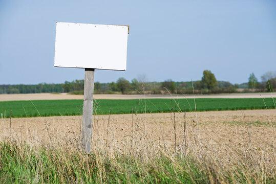 A Blank White Sign Is In Front Of The Land. Land For Sale.