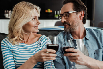 Beautiful woman smiling at husband while toasting with wine at home