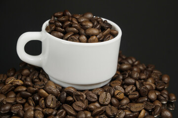 White mug with coffee grains sprinkled with coffee grains on a background