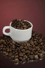 White mug with coffee grains sprinkled with coffee grains on a background