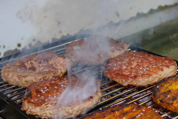 vegetarian and meat cutlets grilled on coal on a small tourist's grill with smoke