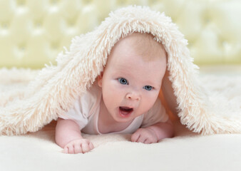 Fototapeta na wymiar Cute little baby girl playing under the blanket