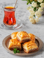 Turkish (eastern) dessert Ramadan Baklava with walnuts and hazelnuts, black strong Turkish tea in a glass of armudu (boomaly). Close-up, shallow depth of field, spring still life