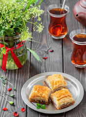 Turkish (eastern) dessert Ramadan Baklava with walnuts and hazelnuts, black strong Turkish tea in a glass of armudu (boomaly). Close-up, shallow depth of field, spring still life