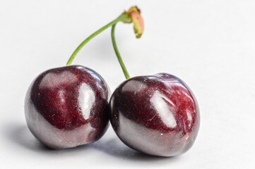 Couple of linked red organic ripe cherries on a white background close up