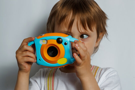 Little cute child girl in white t-shirt take picture on colorful photo camera