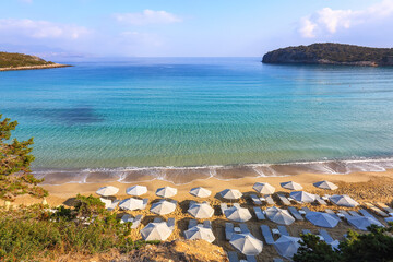 Fantastic white sand, sea and mountain. Empty beach with umbrellas and deck chairs closed. 2020 summer quarantine travel. Beautiful summertime view seascape. Relax places island Crete, Greece.