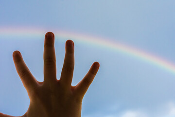 a girl who stretches out her hand to the rainbow. Natural phenomenon.