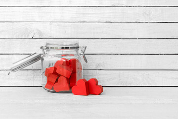 Red Heart Shaped made from paper in bottle glass over white wood background