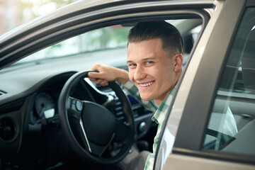 Fototapeta na wymiar Happy man in car in dealership.