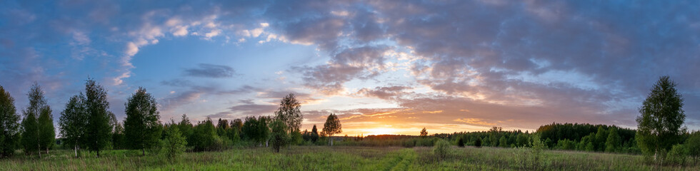 Sunset landscape panorama of summer meadow under blue sky with clouds