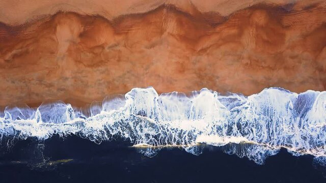 Flying over a sandy beach. Waves break on a sandy beach on the Atlantic coast, aerial View. Nazare, Portugal.