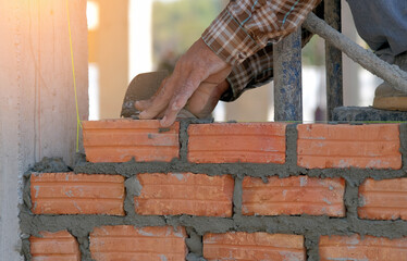 Industrial worker using trowel and tools for building exterior walls with bricks