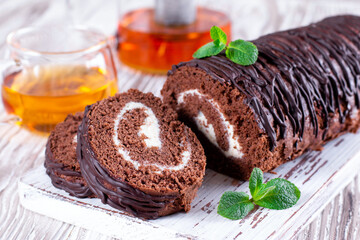 Delicious chocolate roll sponge cake with vanilla cream and mint leaves.