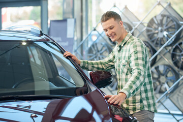 Fototapeta na wymiar Smiling man checking car in dealership.