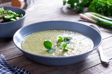 Bowl of broccoli and green peas cream soup on wooden table