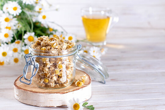 Dried chamomile in the jar on the wooden table. Organic Chamomile Tea in cup and flowers. Copy space