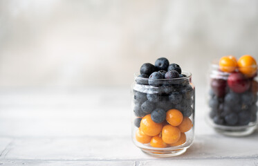 blueberries and physalis berries in a glass jar on a white background
