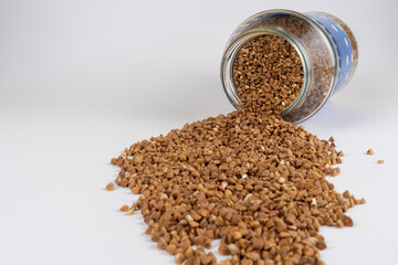 Buckwheat kernels pour out from a glass jar, agronomy world crop
