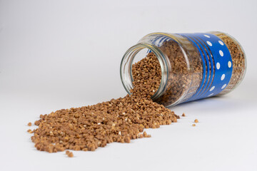 Buckwheat kernels pour out from a glass jar, agronomy world crop