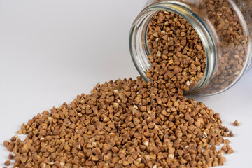 Buckwheat kernels pour out from a glass jar, agronomy world crop