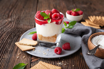 No bake cheesecake dessert in a glass jar topped with raspberry puree and fresh berries