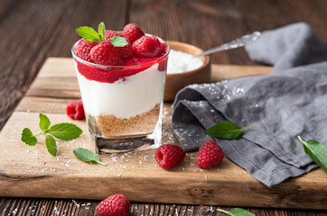 No bake cheesecake dessert in a glass jar topped with raspberry puree and fresh berries