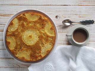 Pastry background.Round sponge cake with pineapple on a white wooden table. Healthy natural food.