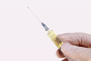 A rubber-gloved hand holds a medical disposable injection syringe on a white background. The concept of vaccination, pandemics, coronavirus, epidemic, pandemic, COVID-19.