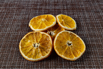 Fototapeta na wymiar Composition of orange dried oranges slices of round shape, preserved color, on a mottled woven brown background. Citrus template for textural background design