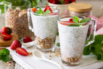 Healthy eating concept breakfast. Strawberry parfait with yogurt, chia seeds, homemade granola and fresh berries on a stone concrete worktop. Copy space.